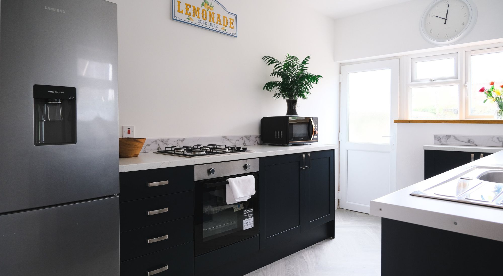 Kitchen with navy cabinets, gas hob, oven and fridge freezer