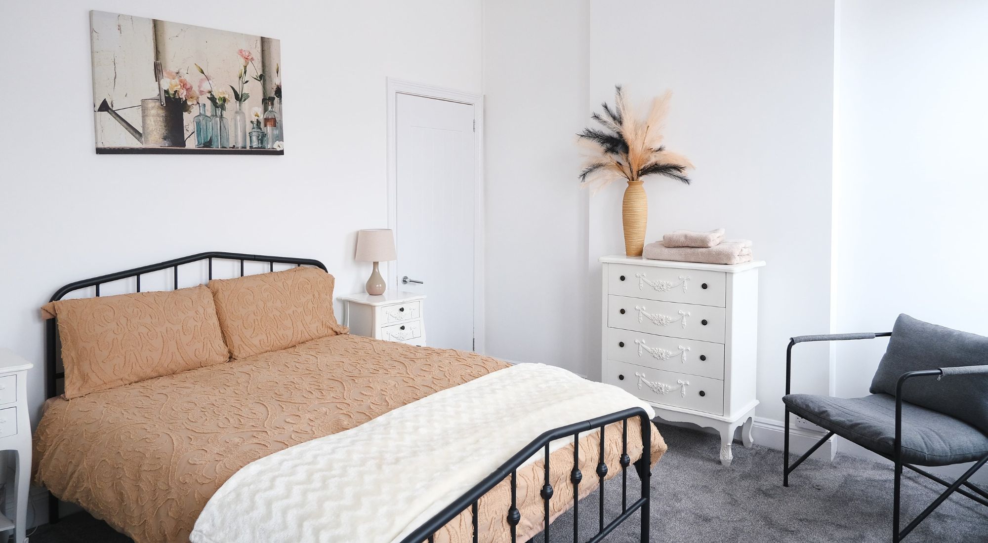Double bedroom with tan bedding and white furniture
