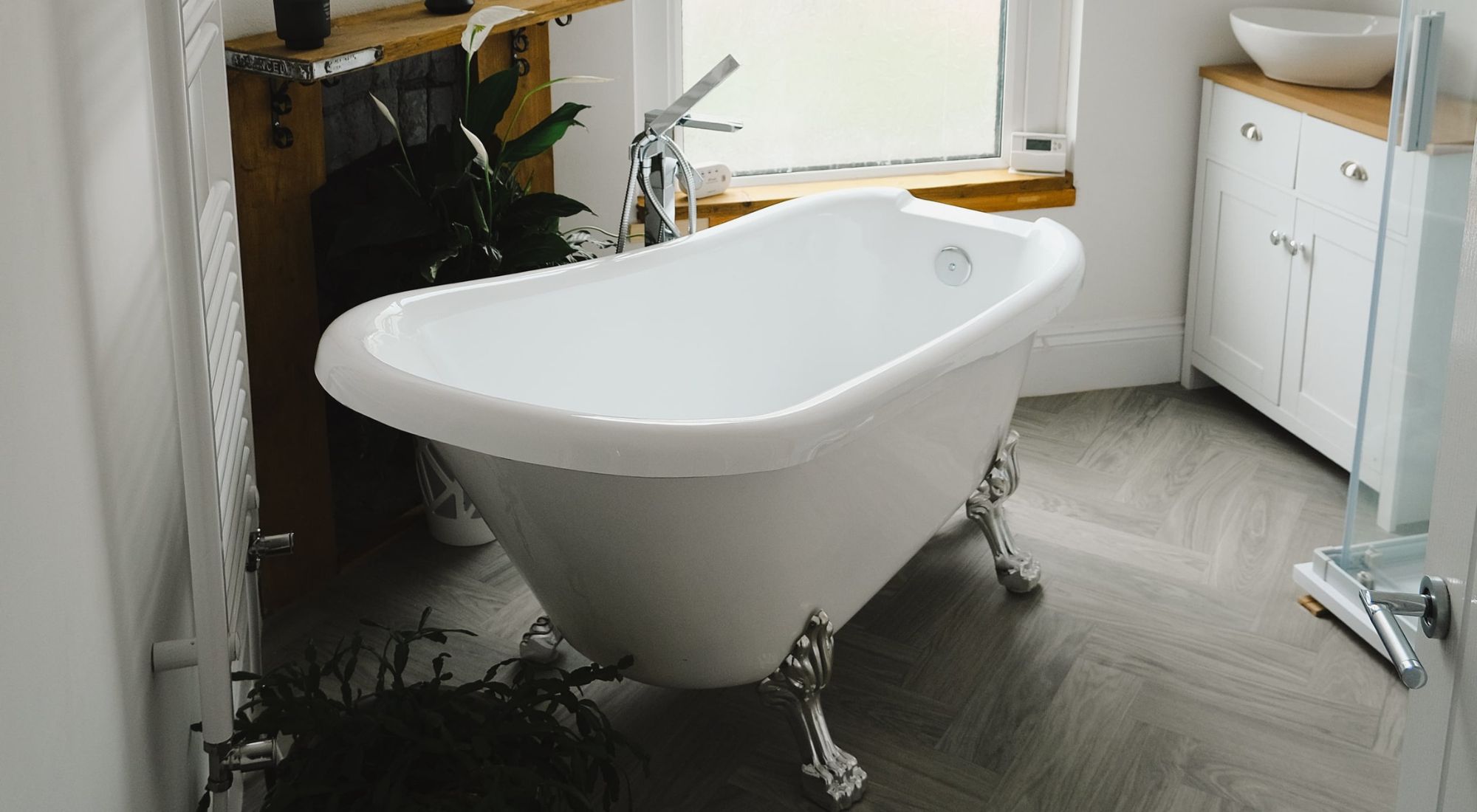 Freestanding roll-top bath on herringbone flooring